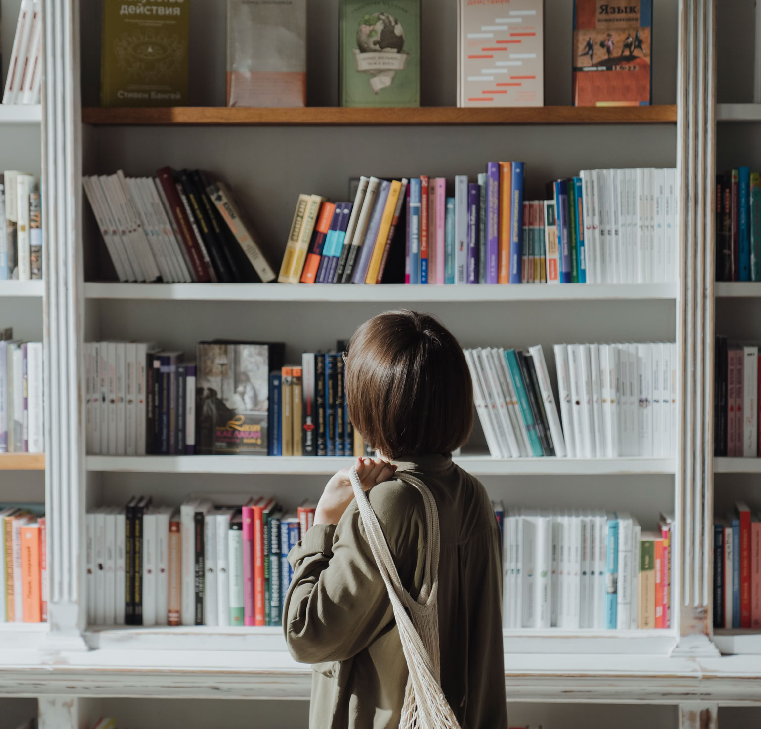 Femme En Manteau Beige Debout Près De L'étagère En Bois Blanc